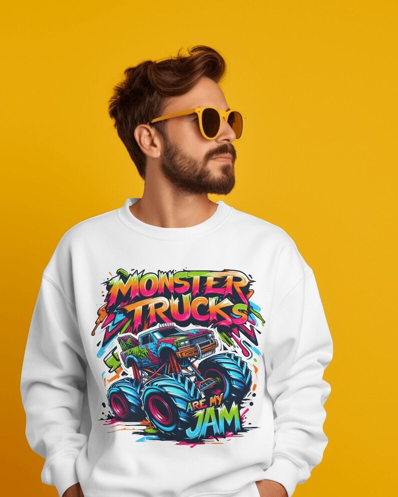 May include: White sweatshirt with a colorful graphic of a monster truck. The graphic includes the text "Monster Trucks Are My Jam".