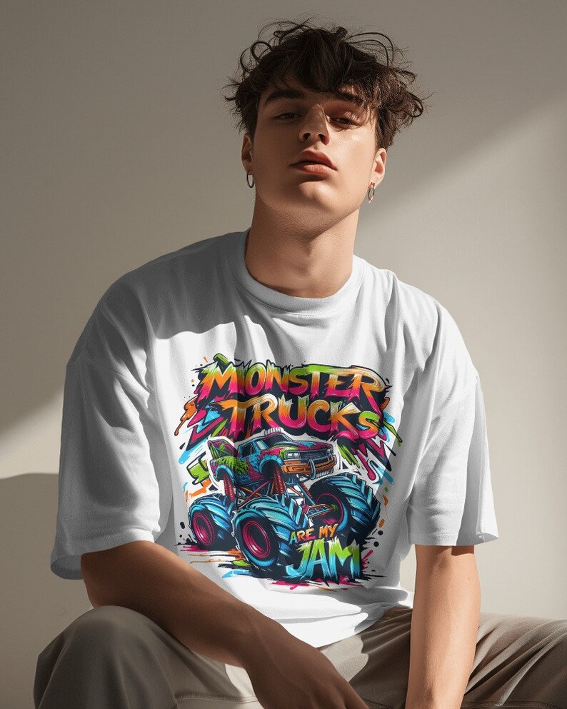 May include: A white t-shirt with a colorful graphic of a monster truck. The graphic includes the text "Monster Trucks Are My Jam".
