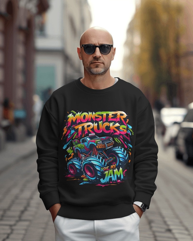 May include: Black sweatshirt with a colorful graphic of a monster truck. The graphic includes the text "Monster Trucks Are My Jam".