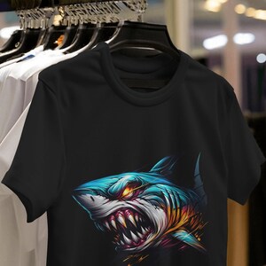 May include: Black t-shirt with a colorful graphic of a shark's head with sharp teeth.