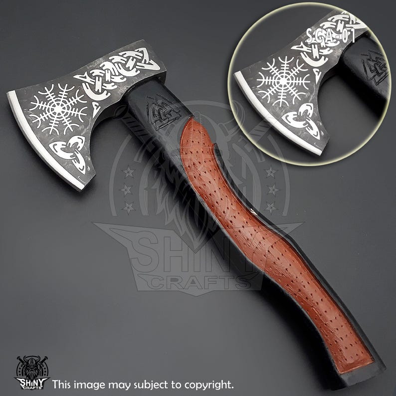 May include: A black and silver axe with a brown leather handle. The axe head features a Viking knotwork design and a runic symbol. The handle has a textured leather grip.