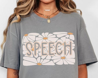 May include: A grey t-shirt with a white daisy print and the word "SPEECH" in orange lettering.