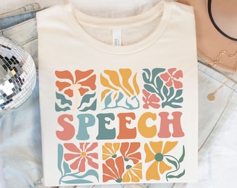 May include: A white t-shirt with a colorful floral design and the word "SPEECH" in a retro font.