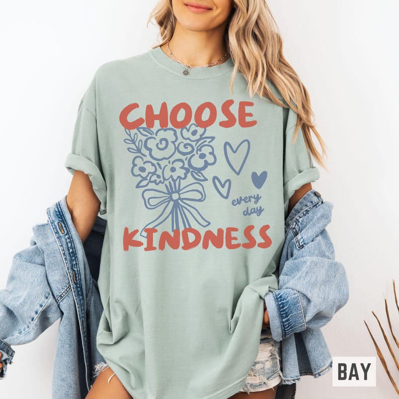 Comfort colors 1717 shirt that says Choose Kindness in large bold hand written font and has doodle images of a bouquet of flowers with a bow and hearts and the words every day written smaller in doodle cursive.