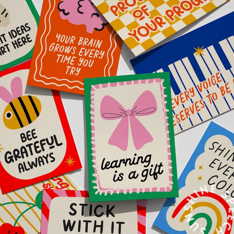 Pu&ograve; includere: Una collezione di biglietti colorati con citazioni e illustrazioni ispiratrici. I biglietti presentano frasi come "Imparare &egrave; un dono", "Sii sempre grato" e "Il tuo cervello cresce ogni volta che ci provi". I disegni includono un fiocco rosa, un'ape e un cervello.