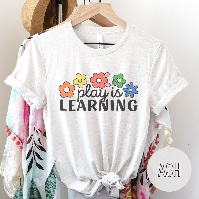 Soft t-shirt that says "Play is Learning" and has cute retro flowers on it for preschool teacher, play therapist, or speech therapist. Gift for teachers or therapists.