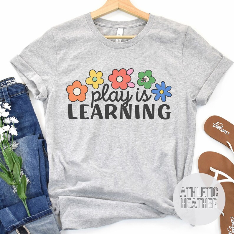 Soft t-shirt that says "Play is Learning" and has cute retro flowers on it for preschool teacher, play therapist, or speech therapist. Gift for teachers or therapists.