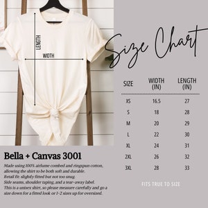 May include: Cream-colored t-shirt on a black hanger. A size chart shows measurements in inches for sizes XS to 3XL. The shirt is made of soft, durable cotton. The chart also includes the width and length of the shirt.