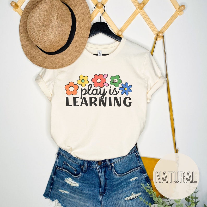 Soft t-shirt that says "Play is Learning" and has cute retro flowers on it for preschool teacher, play therapist, or speech therapist. Gift for teachers or therapists.