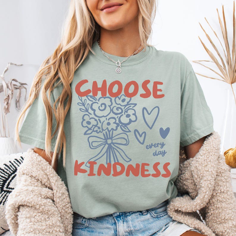 Comfort colors 1717 shirt that says Choose Kindness in large bold hand written font and has doodle images of a bouquet of flowers with a bow and hearts and the words every day written smaller in doodle cursive.