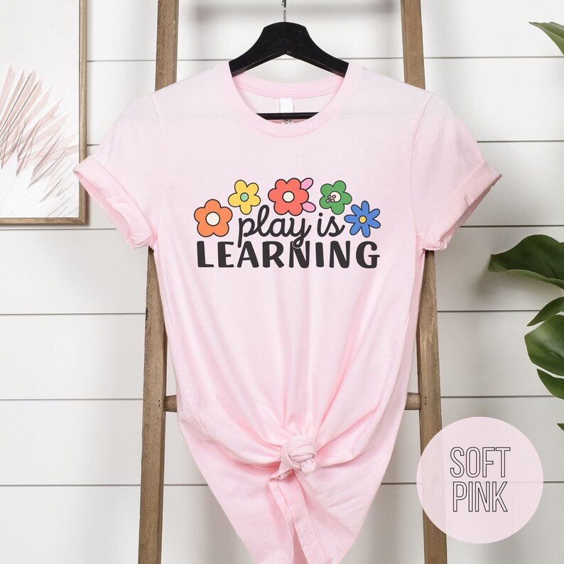 Soft t-shirt that says "Play is Learning" and has cute retro flowers on it for preschool teacher, play therapist, or speech therapist. Gift for teachers or therapists.