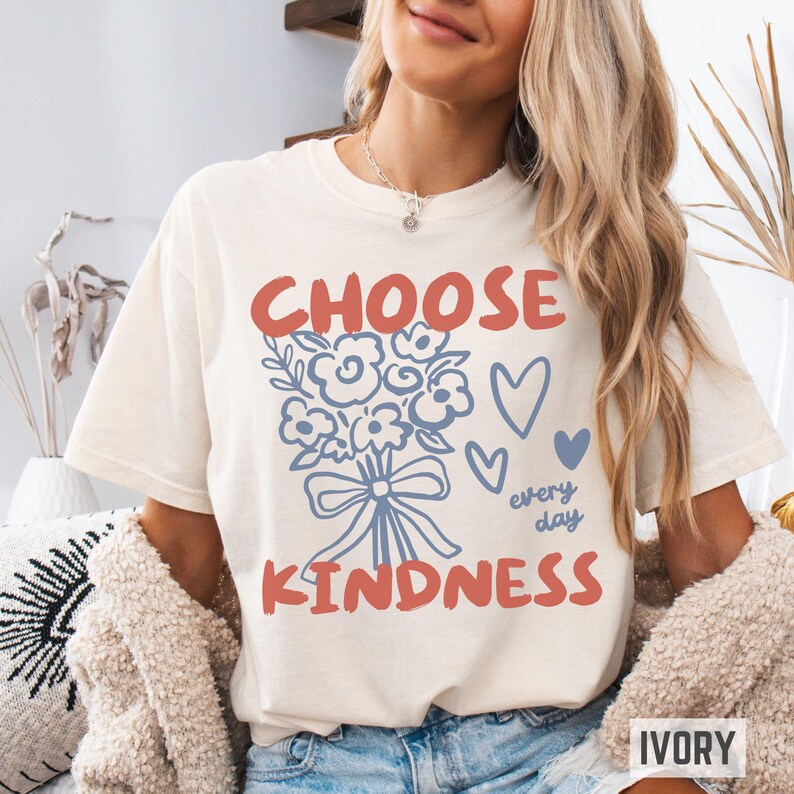 Comfort colors 1717 shirt that says Choose Kindness in large bold hand written font and has doodle images of a bouquet of flowers with a bow and hearts and the words every day written smaller in doodle cursive.