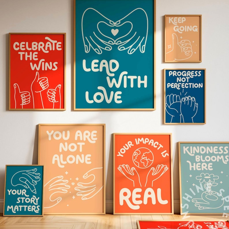 May include: A collection of framed art prints with motivational quotes and illustrations. The prints feature phrases like "Lead With Love," "Your Story Matters," and "Kindness Blooms Here." The color palette includes red, teal, orange, and peach tones.