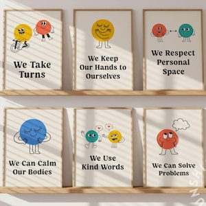 May include: Six framed posters with positive messages. Each poster features a colorful, cartoon-style character and a phrase such as "We Take Turns" and "We Can Solve Problems." The posters are displayed on wooden shelves against a white wall.