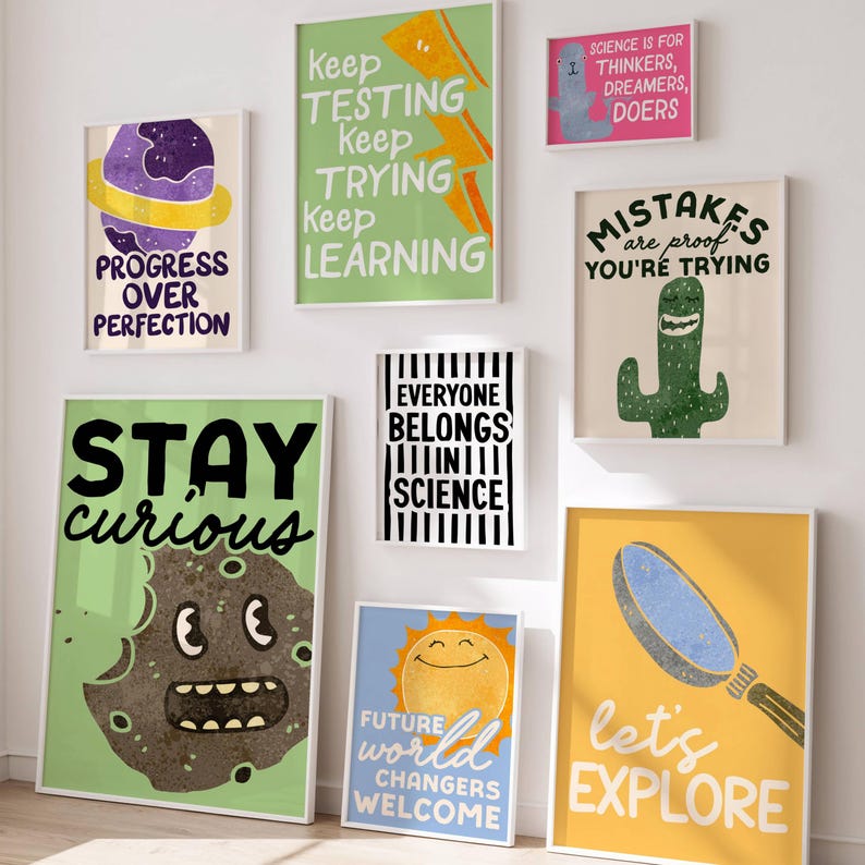 May include: A collection of framed art prints with inspirational quotes and whimsical illustrations. The prints feature phrases like "Stay Curious," "Let's Explore," and "Progress Over Perfection." The color palette includes green, yellow, blue, and pink.