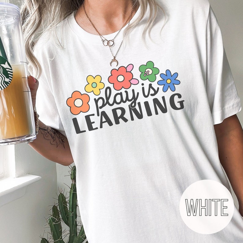Woman wearing t-shirt that says "Play is Learning" and has cute retro flowers on it for preschool teacher, play therapist, or speech therapist. Gift for teachers or therapists.
