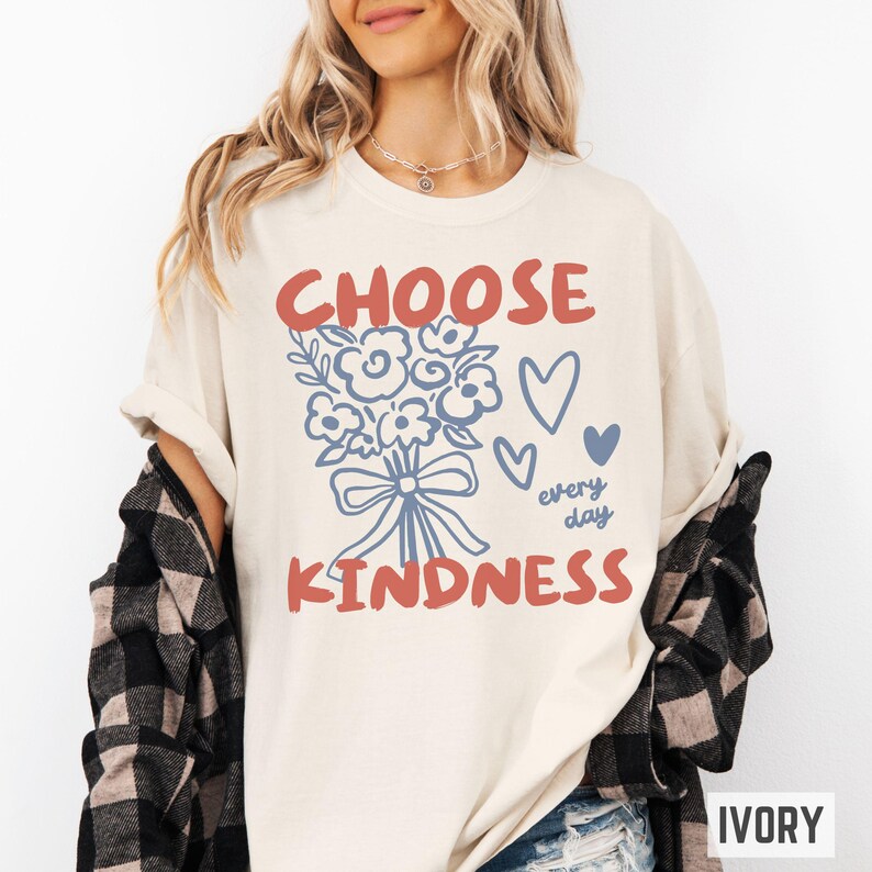 Comfort colors 1717 shirt that says Choose Kindness in large bold hand written font and has doodle images of a bouquet of flowers with a bow and hearts and the words every day written smaller in doodle cursive.