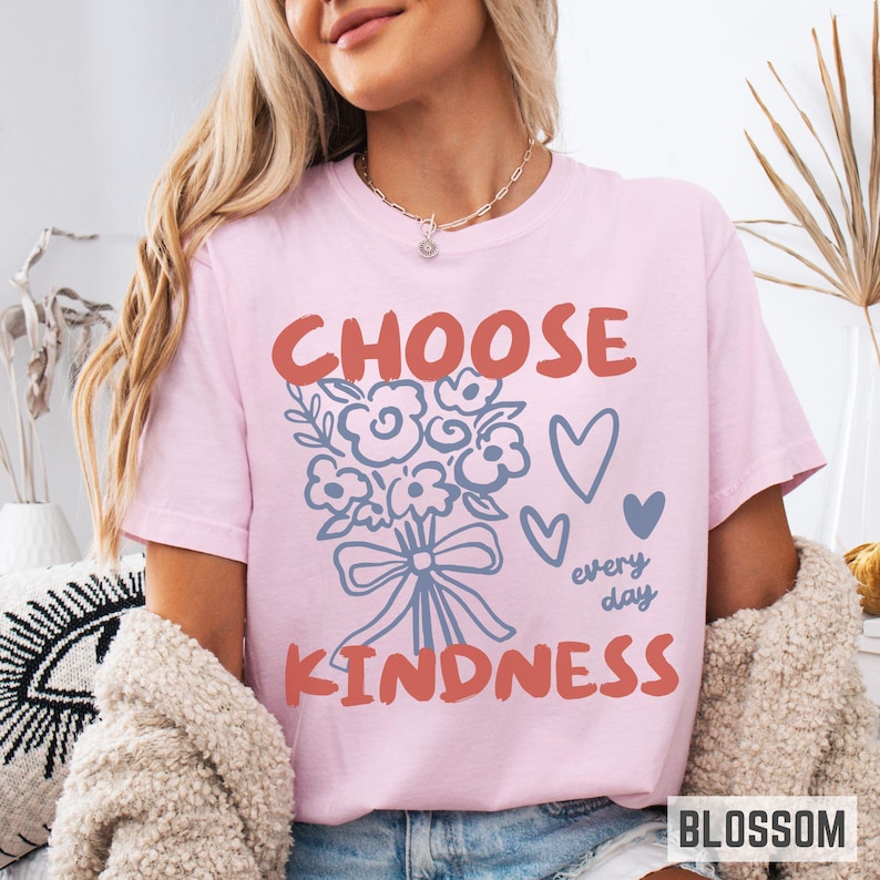 Comfort colors 1717 shirt that says Choose Kindness in large bold hand written font and has doodle images of a bouquet of flowers with a bow and hearts and the words every day written smaller in doodle cursive.
