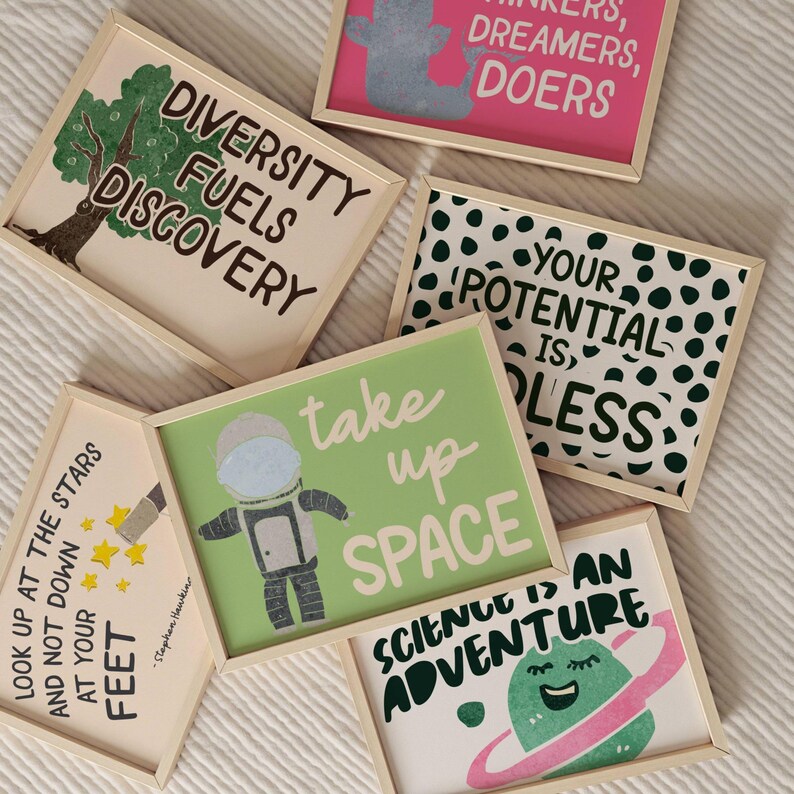 May include: A collection of framed art prints with inspirational quotes and illustrations. The prints feature phrases like "Diversity Fuels Discovery" and "Take Up Space." The color palette includes green, pink, and white, with a light wood frame.