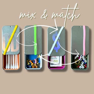 May include: Four silver tins with different colored elastic bands and various items inside. The tins are labeled with the letters "CD", a dollar sign, and a series of letters. The text "mix & match" is written above the tins.