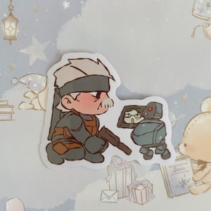May include: A cartoon sticker featuring a character with a bandana and a gun, looking at a small robot with a screen. The robot is holding a book that says "Stars".