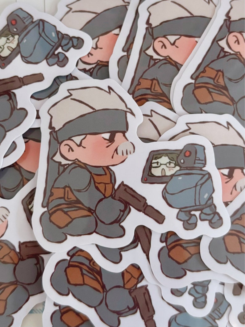 May include: A stack of stickers featuring a cartoon character wearing a grey and brown outfit and a black eye patch. The character is holding a gun and standing next to a small robot.