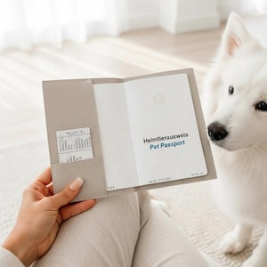 May include: A light beige, textured protective cover holding an open pet passport. The passport features the text Heimtierausweis Pet Passport on the white inner page, along with a small card tucked into the left-hand side pocket slot.