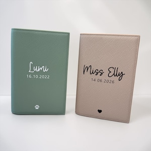 May include: Two rectangular passport holders with a textured finish. The left holder is sage green with white text reading Lumi 16.10.2022 and a paw print. The right holder is beige with black text reading Miss Elly 14.06.2026 and a small heart icon.