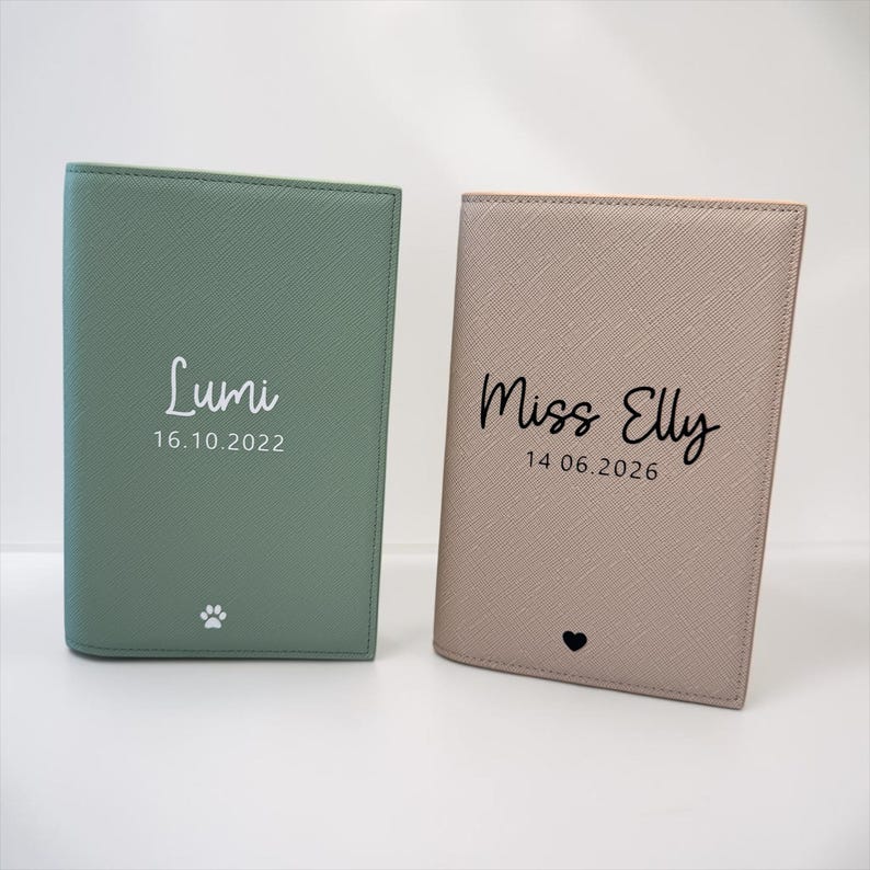 May include: Two rectangular passport holders with a textured finish. The left holder is sage green with white text reading Lumi 16.10.2022 and a paw print. The right holder is beige with black text reading Miss Elly 14.06.2026 and a small heart icon.