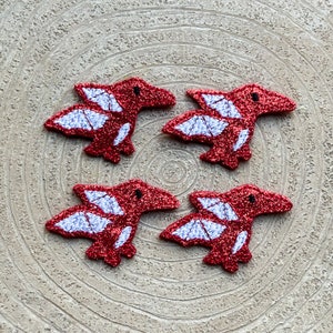 May include: Four red and white glitter pterodactyl iron-on patches. The patches are about 2 inches tall and 3 inches wide.