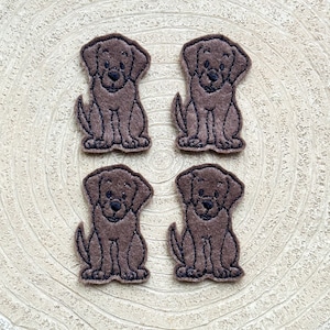 May include: Four brown felt appliques of a chocolate Labrador Retriever dog. Each applique is about 2 inches tall and 1.5 inches wide.