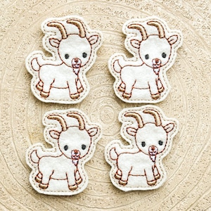 May include: Four white felt appliques of cartoon goats with brown embroidered details. Each goat has a brown nose, eyes, and hooves. The goats are looking to the right.