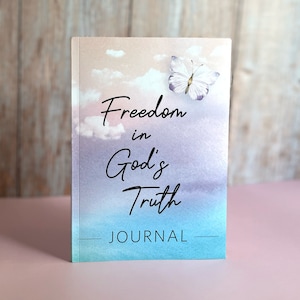 May include: A blue and purple watercolor journal with a butterfly on the cover. The journal has the text "Freedom in God's Truth" and "JOURNAL" on the cover.