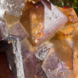 May include: A large cluster of purple and orange fluorite crystals. The crystals are intergrown and have a variety of shapes and sizes. The fluorite is translucent and has a glassy luster.
