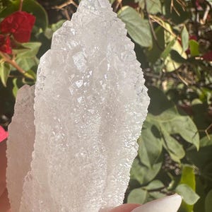 Puede incluir: Un gran c&uacute;mulo de cristales blancos transparentes con una superficie rugosa y texturizada. El cristal tiene forma de abanico o de hoja.