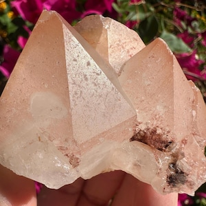 May include: A cluster of peach-colored quartz crystals with sharp, geometric points. The crystals have a translucent quality, with some areas appearing more opaque. The overall structure is complex and natural, showcasing the beauty of raw minerals.