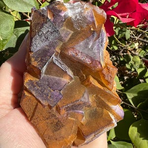 May include: A large, natural, purple and orange fluorite crystal cluster. The crystal has a rough, textured surface and is a beautiful example of this mineral.