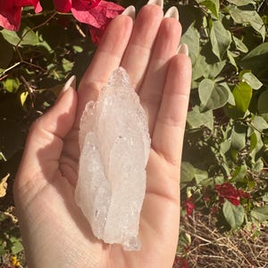 Puede incluir: Un gran c&uacute;mulo de cristal de cuarzo transparente con una textura rugosa y natural. El cristal es transl&uacute;cido y tiene un color blanco lechoso.