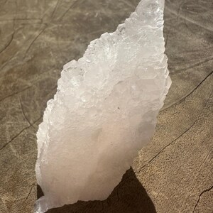 Puede incluir: Un gran c&uacute;mulo de cristales rosa con una punta puntiaguda. El cristal es transl&uacute;cido y tiene una superficie rugosa y texturizada.
