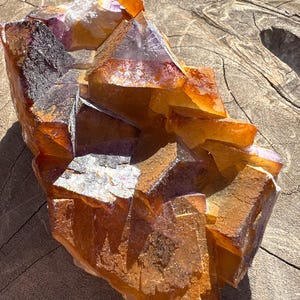 May include: A large, orange and purple fluorite crystal cluster with a rough, natural texture. The crystal is composed of many individual crystals that have grown together.