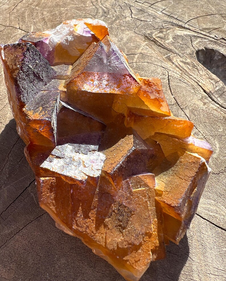 May include: A large, orange and purple fluorite crystal cluster with a rough, natural texture. The crystal is composed of many individual crystals that have grown together.