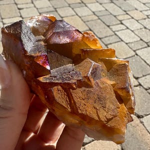 May include: A cluster of orange and purple fluorite crystals with a rough, textured surface.