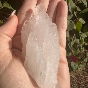 Puede incluir: Un gran c&uacute;mulo de cristales blancos transparentes con una superficie rugosa y texturizada. El cristal tiene forma de pir&aacute;mide y tiene m&uacute;ltiples puntas.