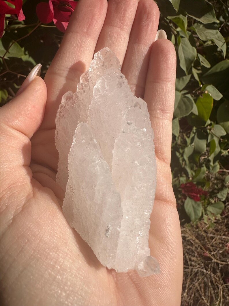 Puede incluir: Un gran c&uacute;mulo de cristales blancos transparentes con una superficie rugosa y texturizada. El cristal tiene forma de pir&aacute;mide y tiene m&uacute;ltiples puntas.