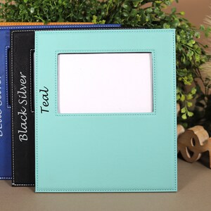 May include: Four picture frames in different colors: bamboo, blue silver, black silver, and teal. Each frame has a stitched border and a white rectangle in the center.