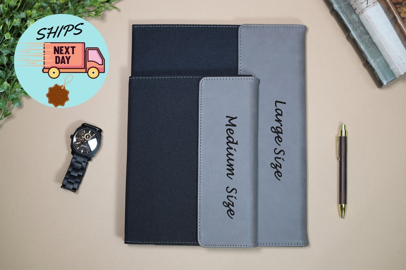 May include: Two black and gray leather notebook covers with the words "Medium Size" and "Large Size" printed on them.