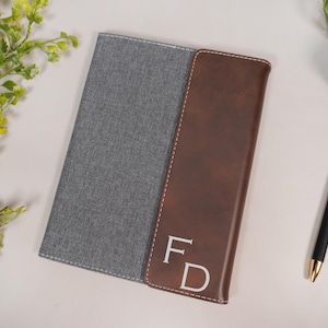 May include: A gray and brown leather journal with the initials "FD" embossed in white on the front cover.