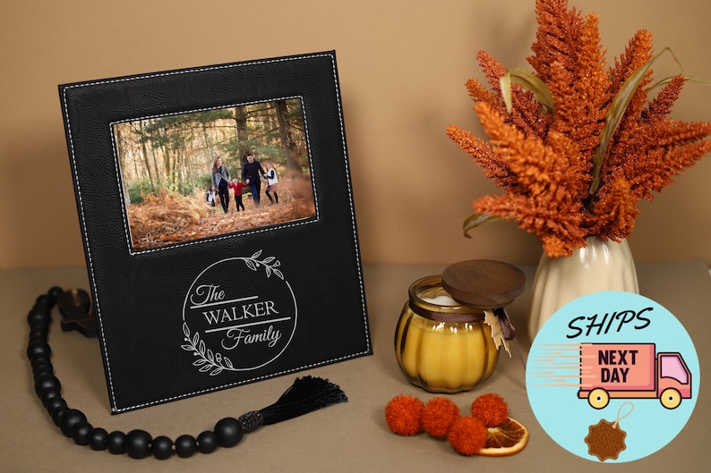 May include: Black leather photo frame with a white stitched border. The frame has a photo of a family in a forest and a personalized inscription that reads "The Walker Family".