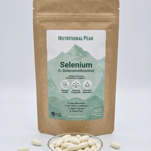 May include: A brown resealable pouch of Nutritional Peak Selenium L-Selenomethionine dietary supplement with a mountain graphic label. In front, a clear glass dish contains numerous white oval softgels, with several more scattered around the base.