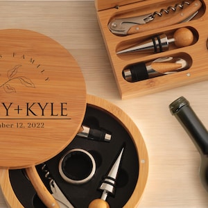 May include: A wooden box with a lid that has the text "SEARS FAMILY HALEY + KYLE December 12, 2022" engraved on it. The box contains a wine opener, a bottle stopper, and a foil cutter.